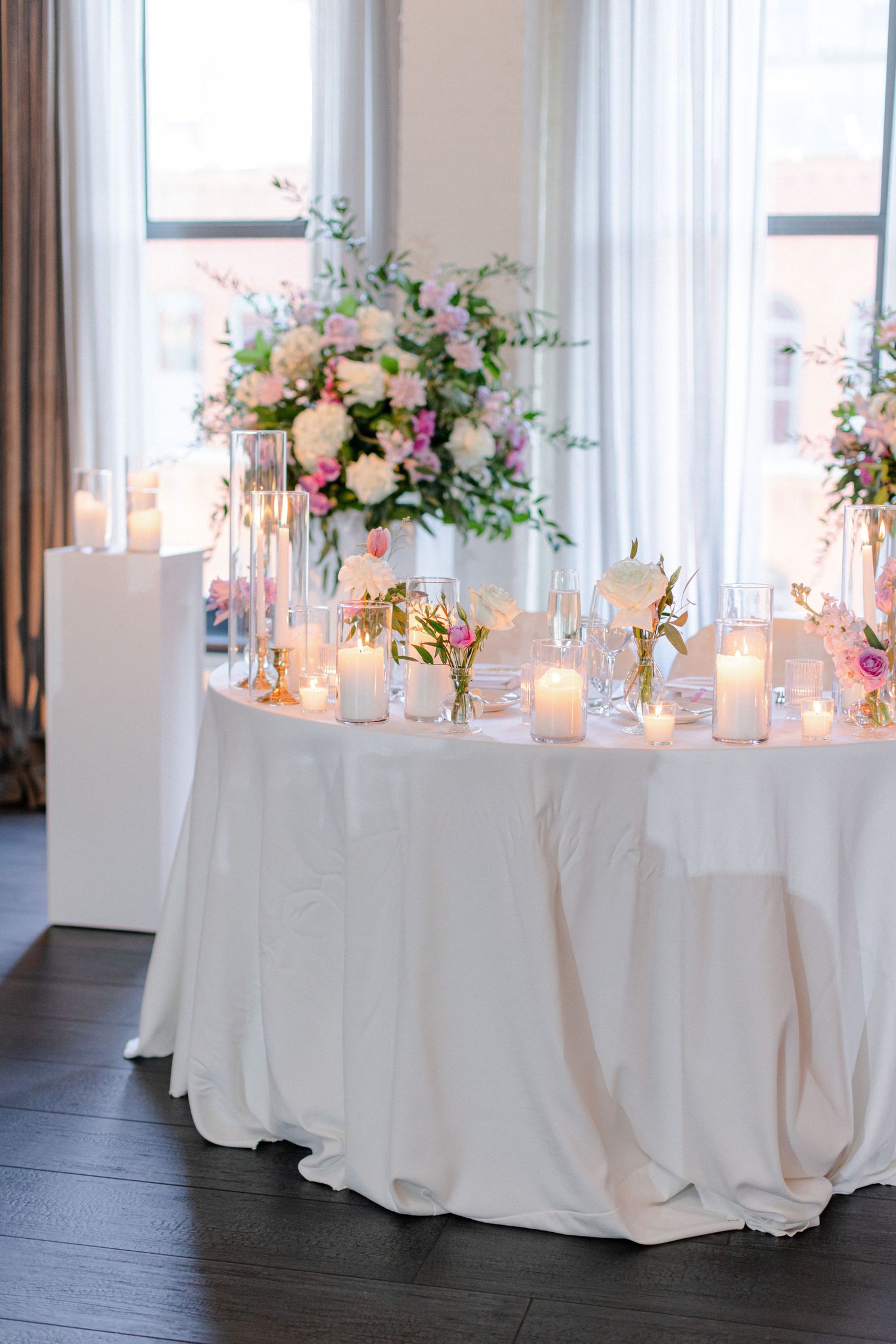 Elegant wedding table decor with white linens, candles and a lush pink and white floral centerpiece.