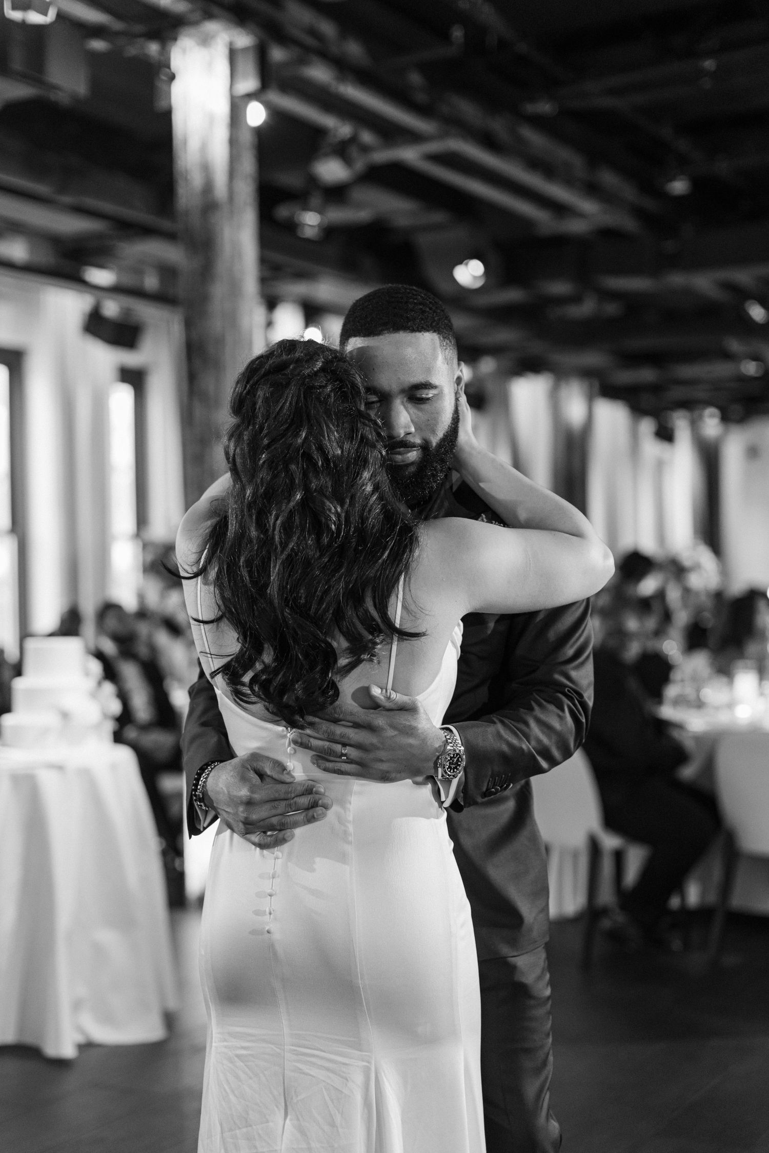 A tender first dance moment between newlyweds at their wedding reception in an industrial-style venue.