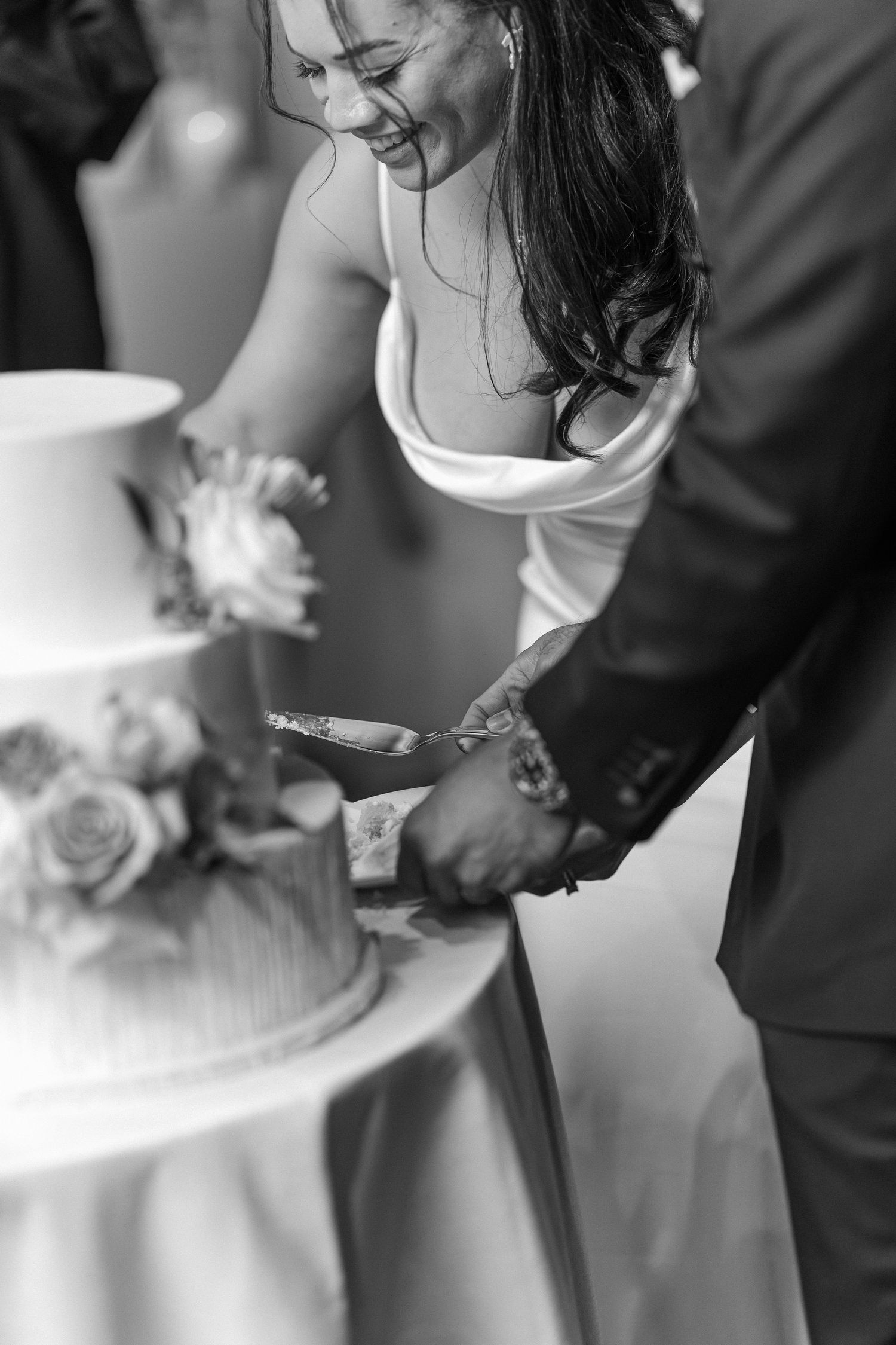 Close-up shot of couple cutting their wedding cake together with silver knife.