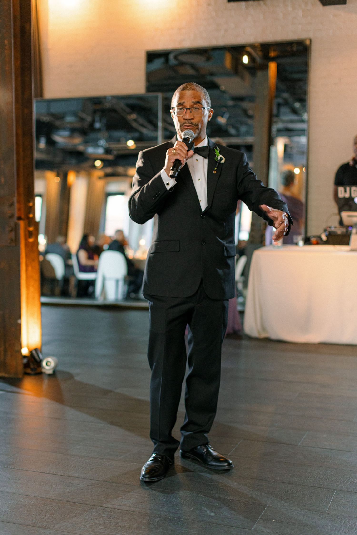 Guest in formal attire gives a speech during wedding reception.