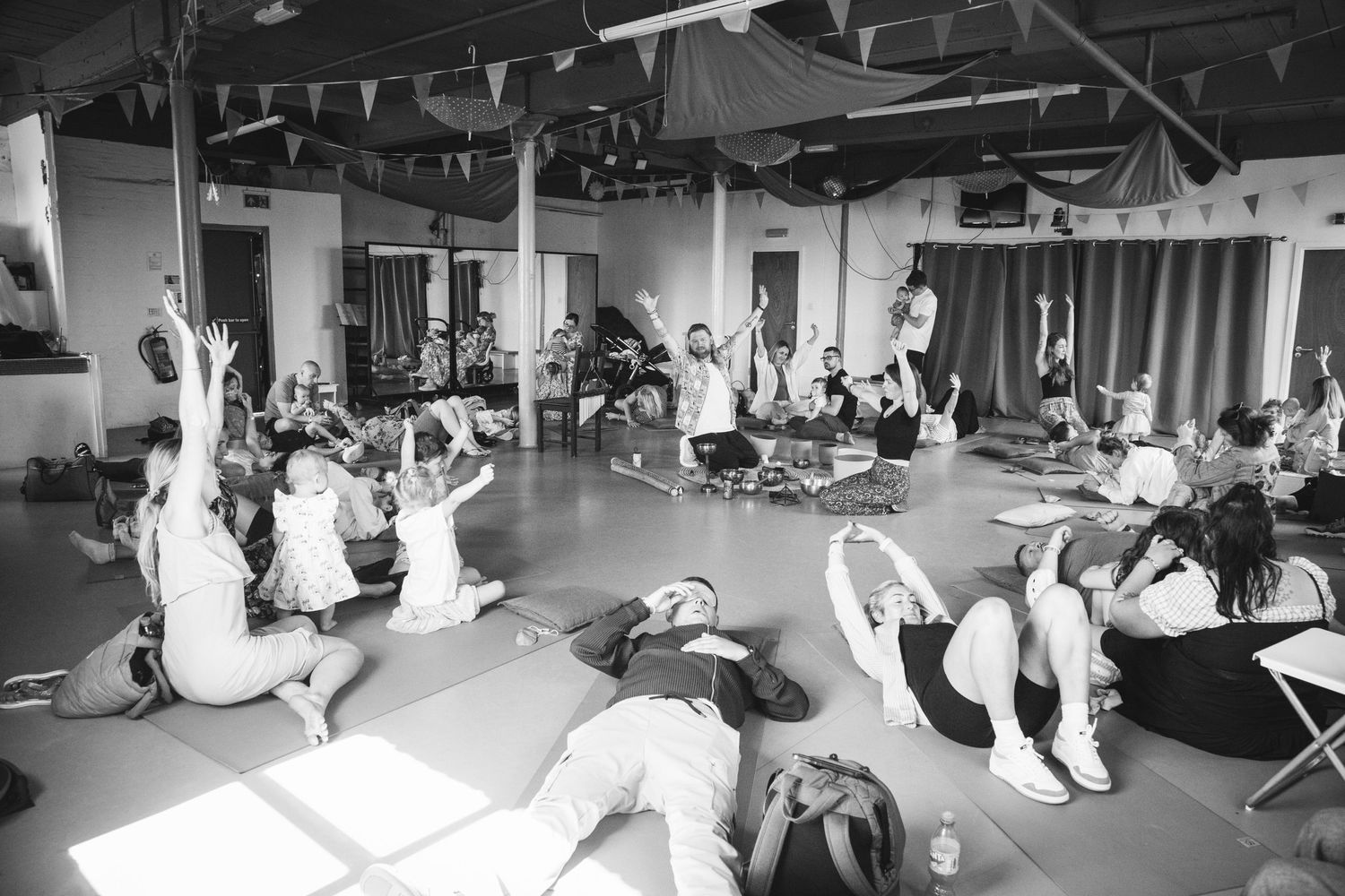 Large group participating in floor exercises during an indoor workshop in black and white.