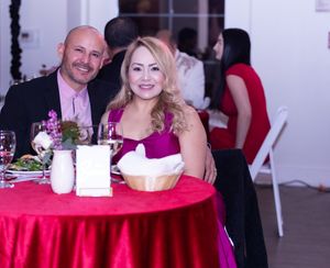 A couple seated at a red-clothed table during an elegant dinner celebration.