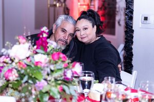 A couple poses together at a formal dinner event with pink floral centerpieces.