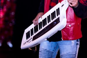 A white electronic keyboard being held against a dark background with red lighting.