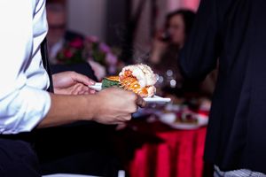 Close-up of hands serving appetizers at an upscale catered event.