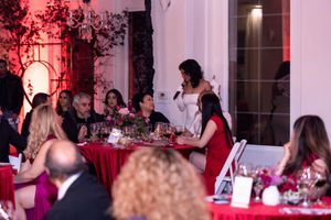Guests dining at tables with red linens during elegant evening event.