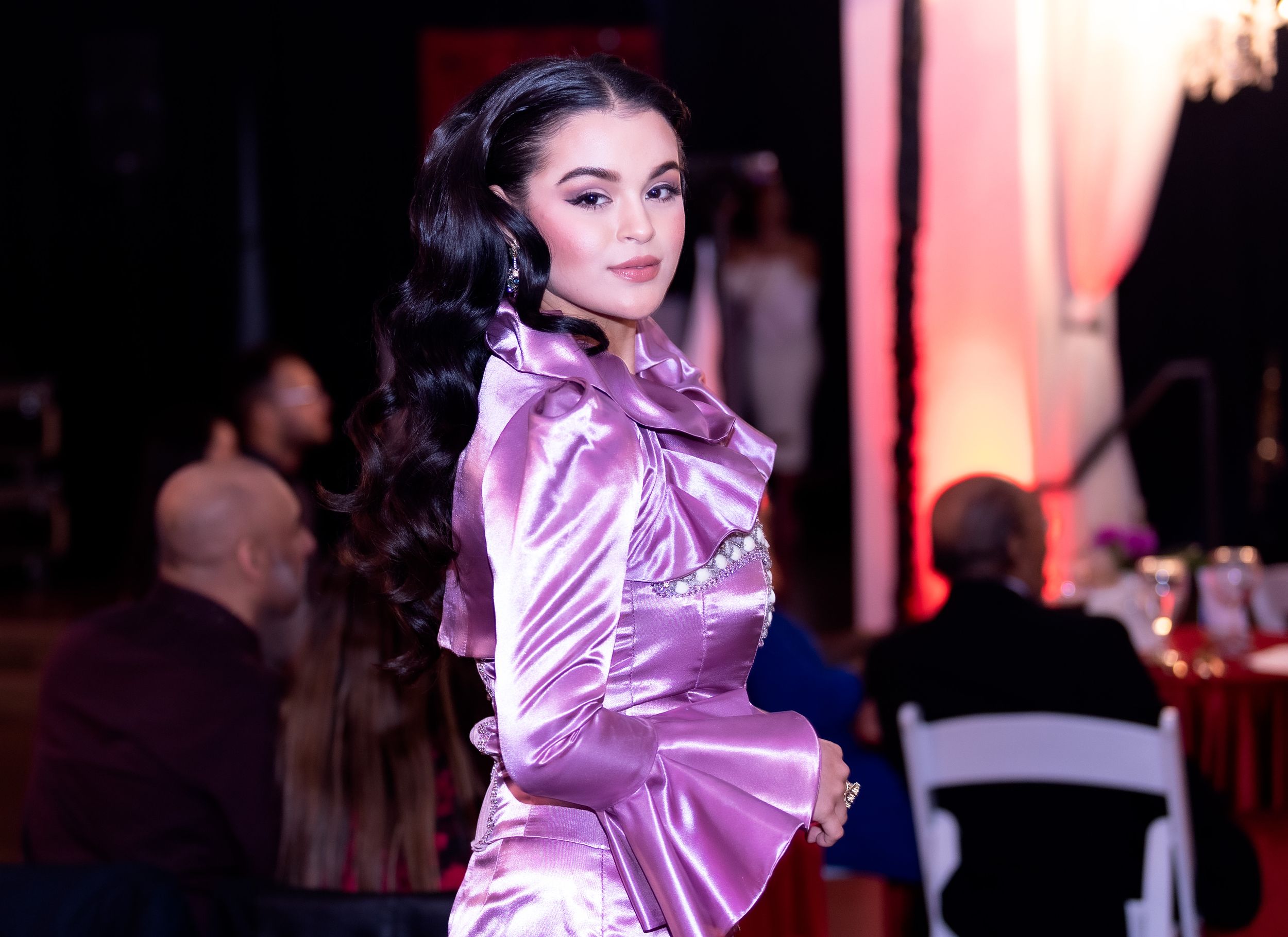 Model poses in shimmering purple satin gown during elegant evening event.