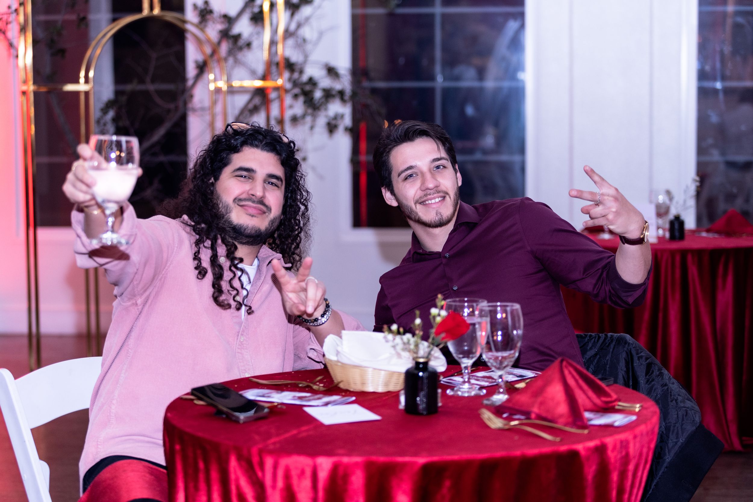 Two friends enjoying dinner at a table with red tablecloth in a festive restaurant setting.