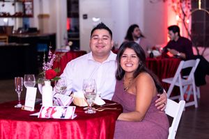 Couple enjoying dinner together at formal event with red tablecloths and wine glasses.