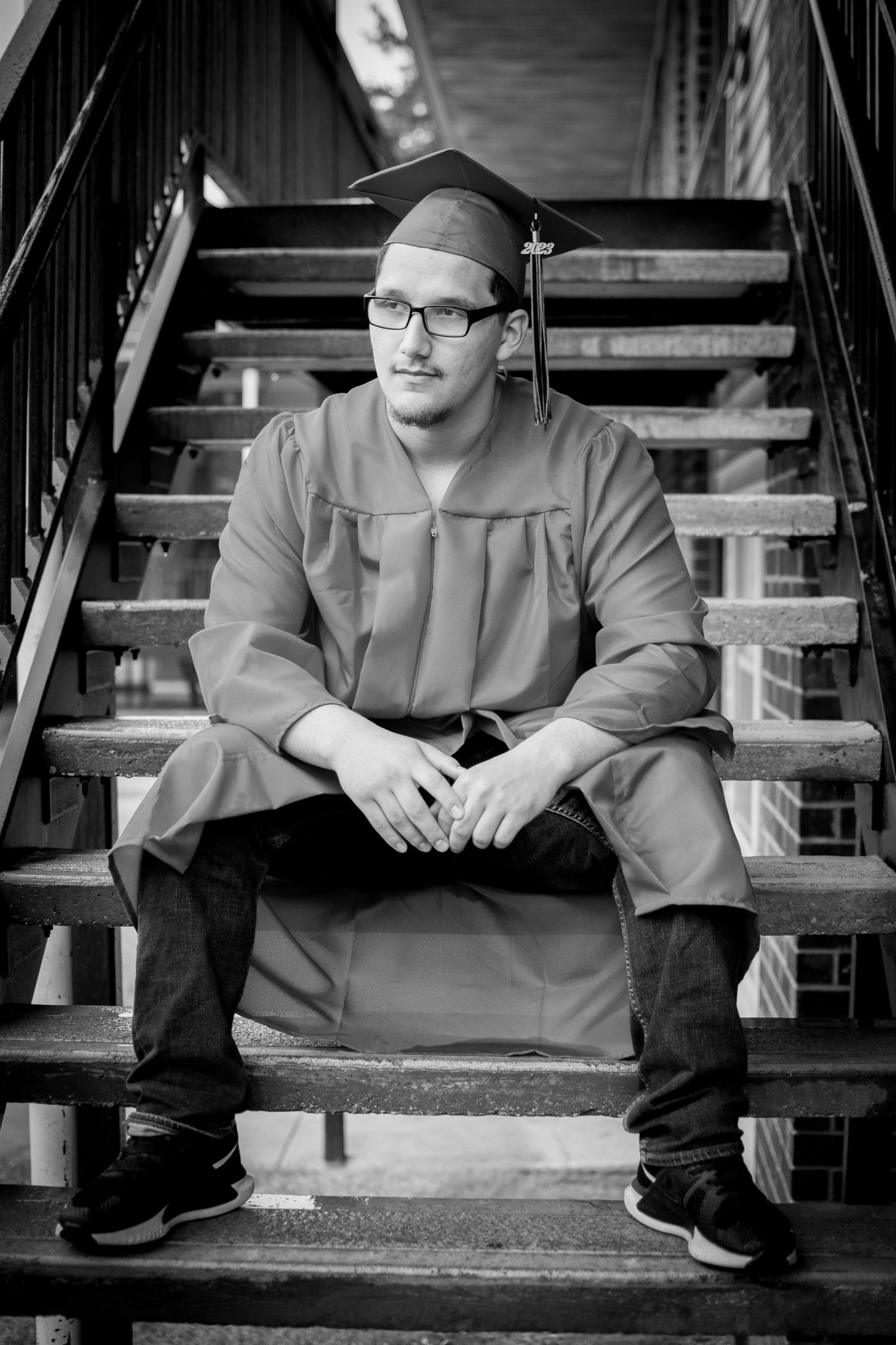 black and white photo of senior sitting on stairs looking out