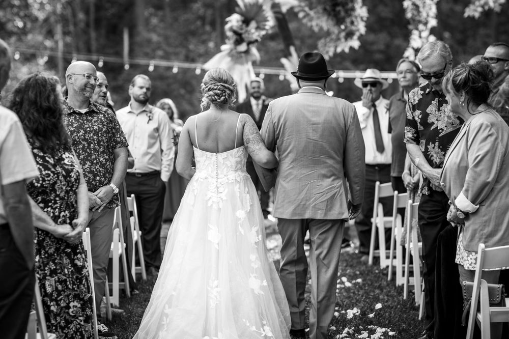 A wedding party celebrates during an outdoor garden reception with guests mingling and dancing in formal attire.