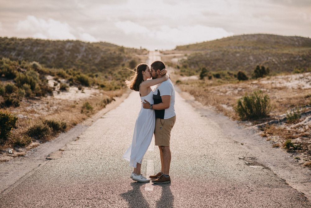 Couple embracing on an empty mountain road surrounded by desert landscape.