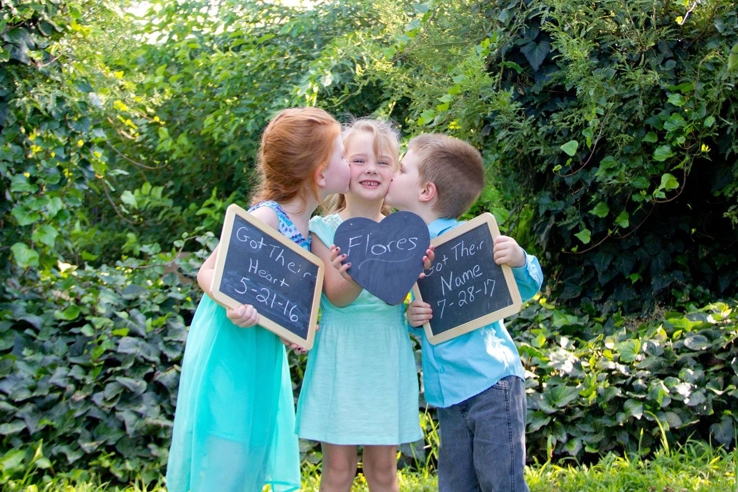 Three children holding chalkboard signs in a garden setting.
kid photography
child photography
Portrait photography
family adoption