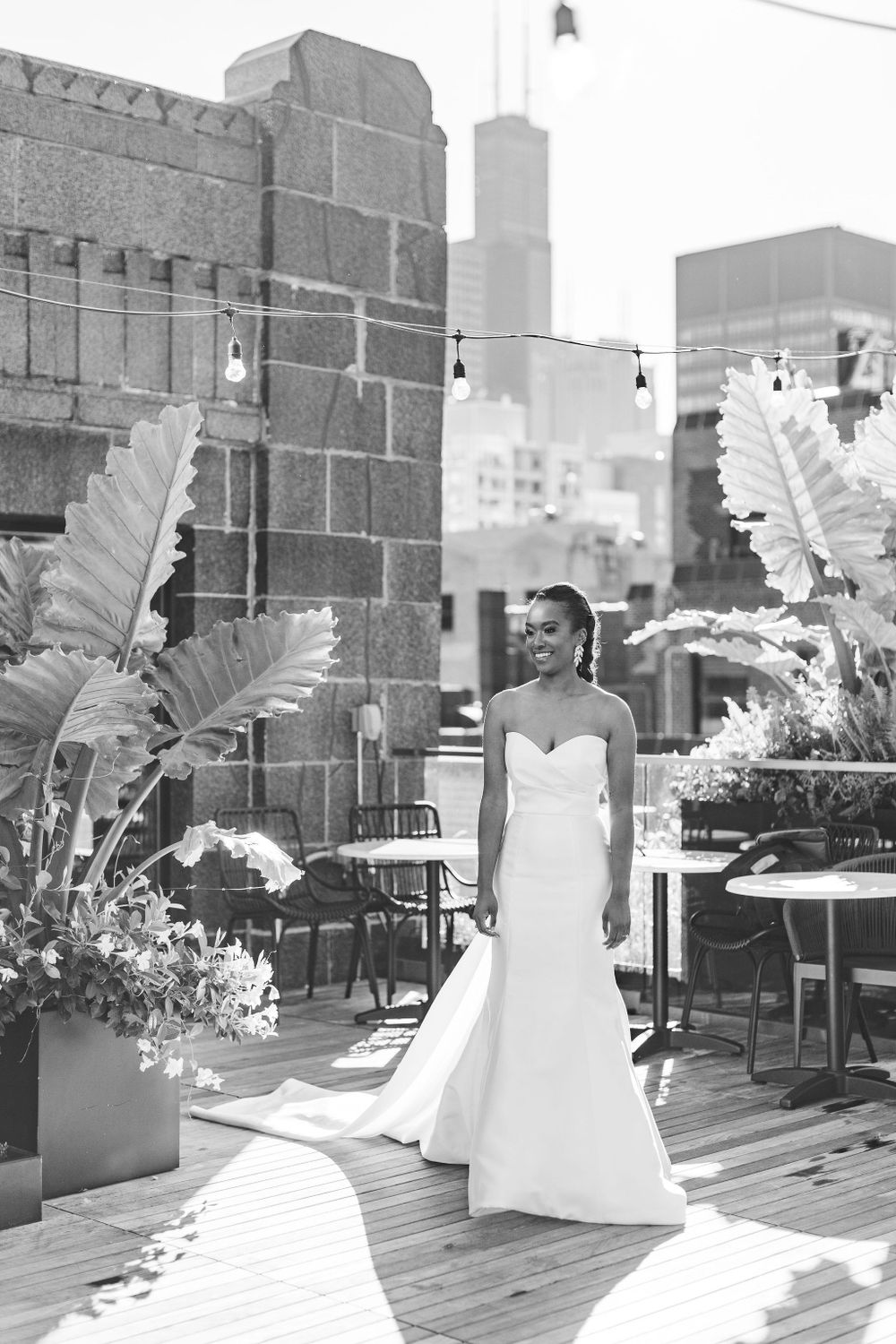 Elegant white wedding gown silhouette against Chicago skyline on rooftop terrace.