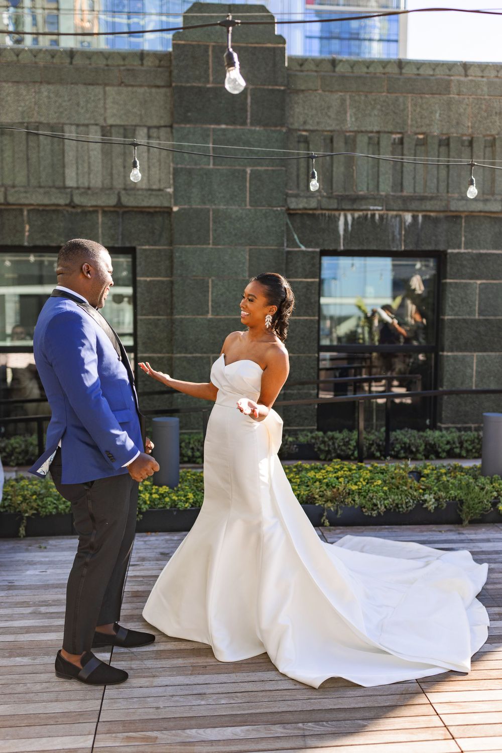 Bride and groom sharing intimate moment during first look on urban rooftop with string lights.