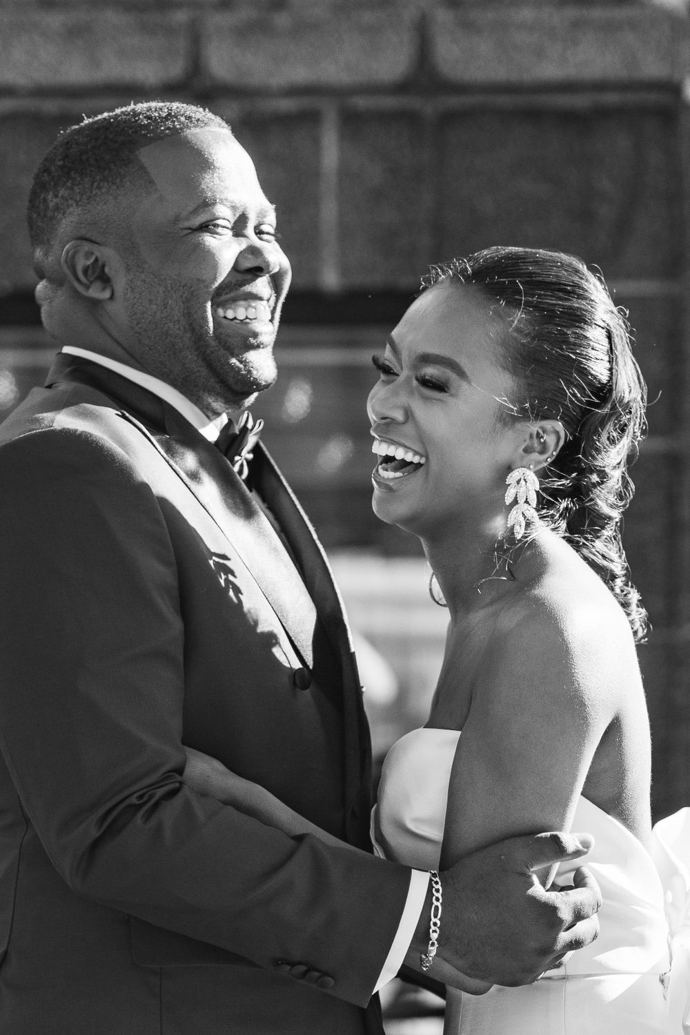 Black and white candid photo of joyful couple sharing laughter during wedding.
