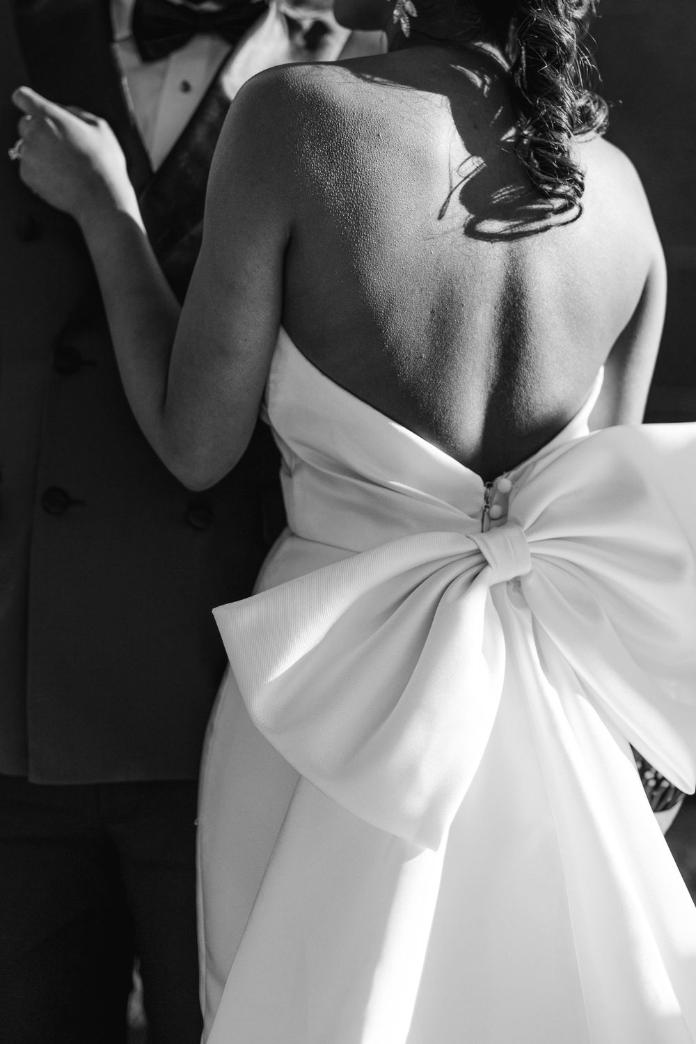 Elegant white wedding dress with dramatic bow detail on open back.