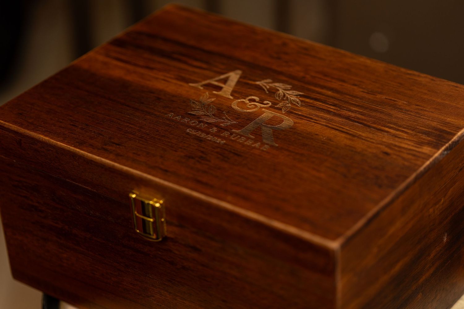 A polished wooden keepsake box with an engraved A&R monogram.