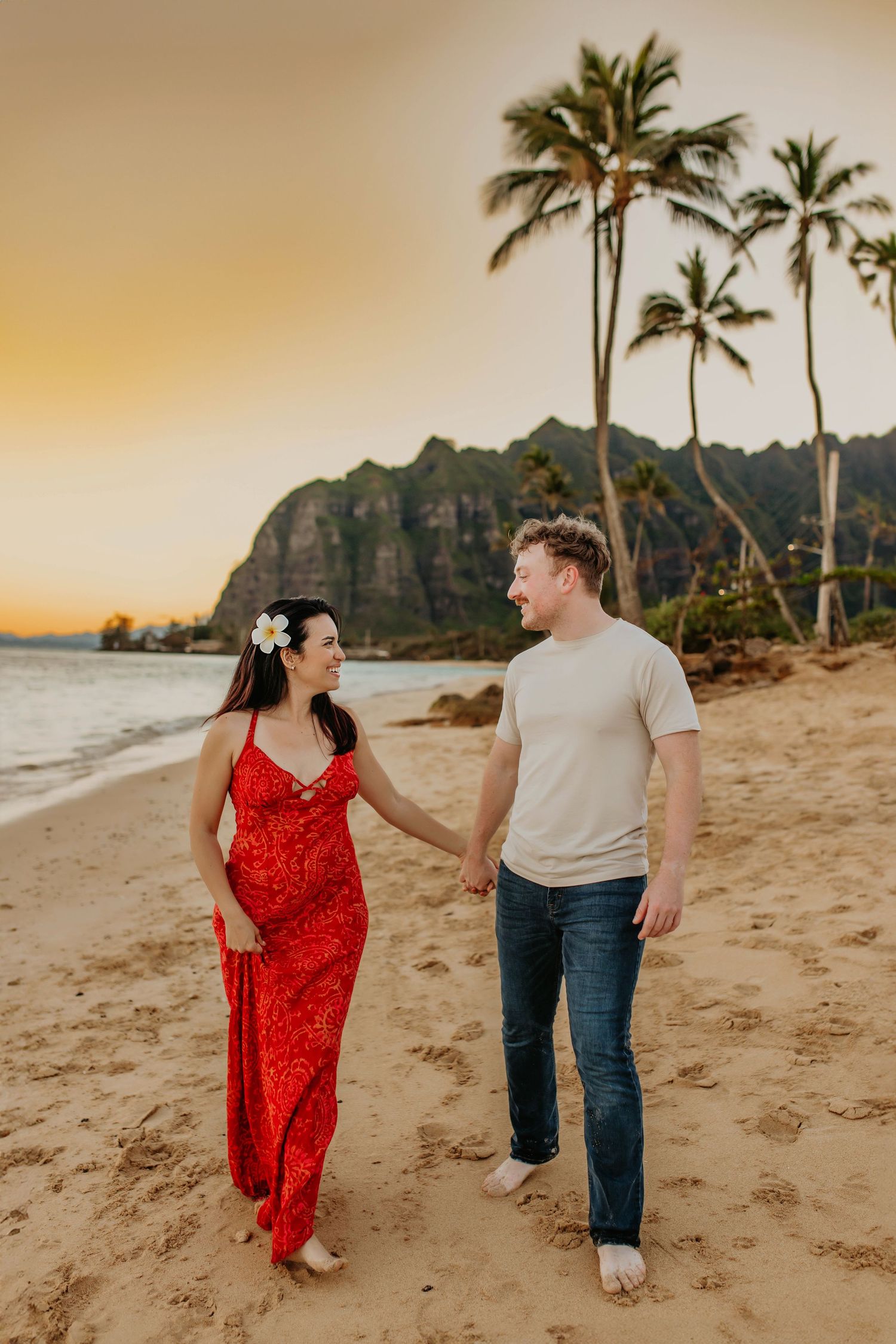 Romantic beach photoshoot at sunset with palm trees and mountains in Hawaii.