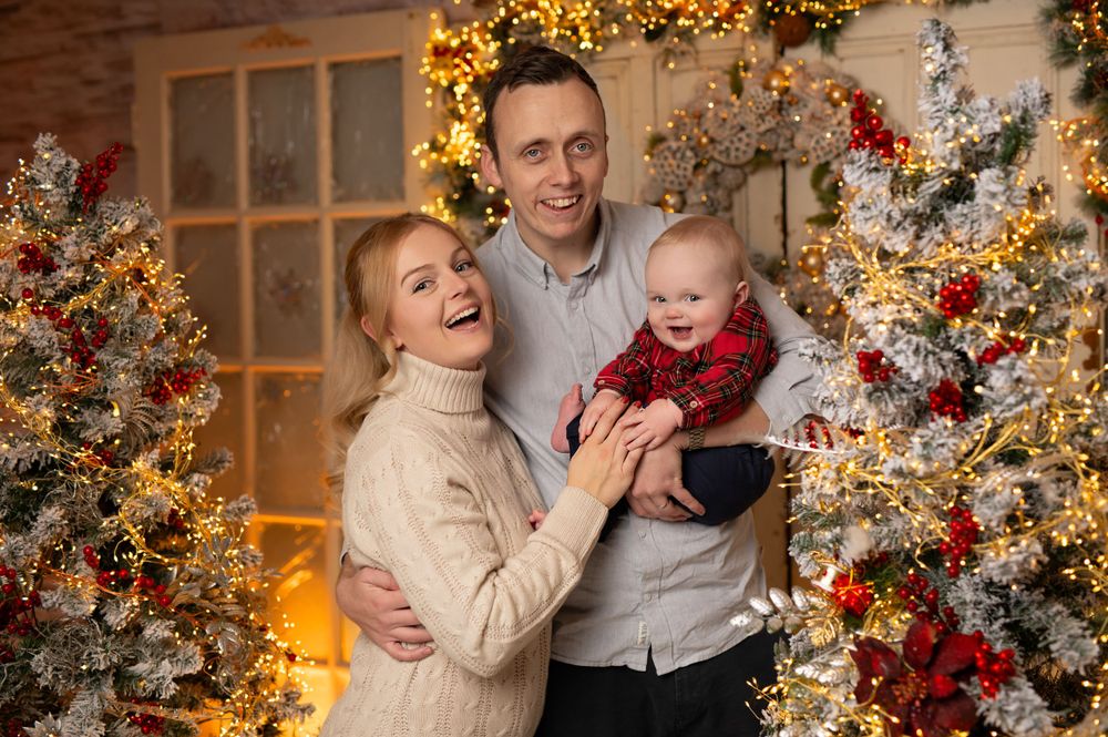 Joyful holiday family moment captured against a backdrop of Christmas decorations and lights.