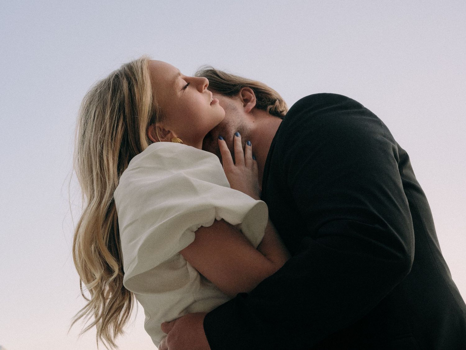 A romantic embrace against a bright sky showing affection and tenderness.