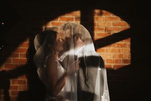 Dramatic silhouette against brick wall with streaming light and shadows creating moody atmosphere.