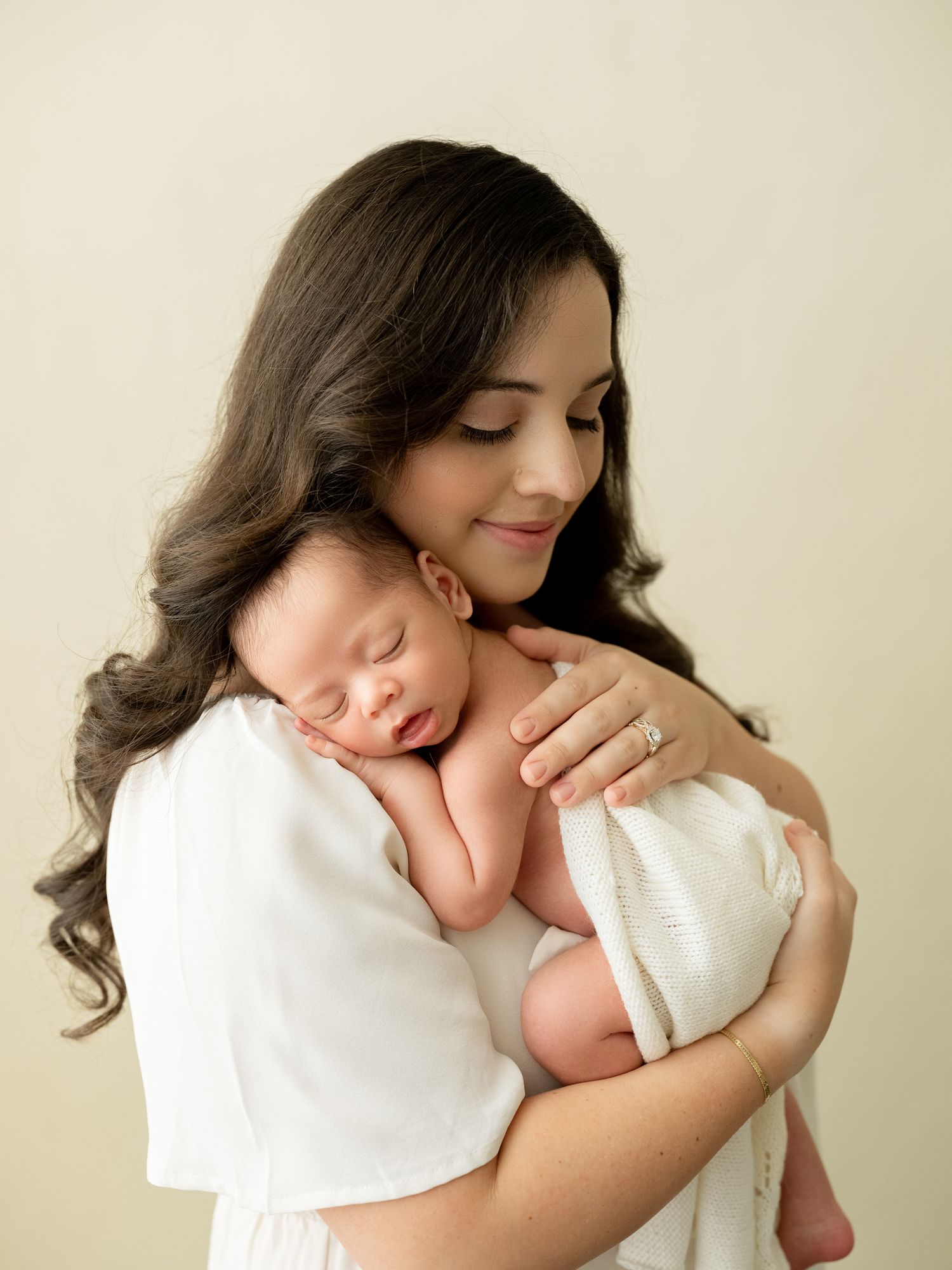 Four sequential photos capturing intimate bonding moments with an infant in a white setting.