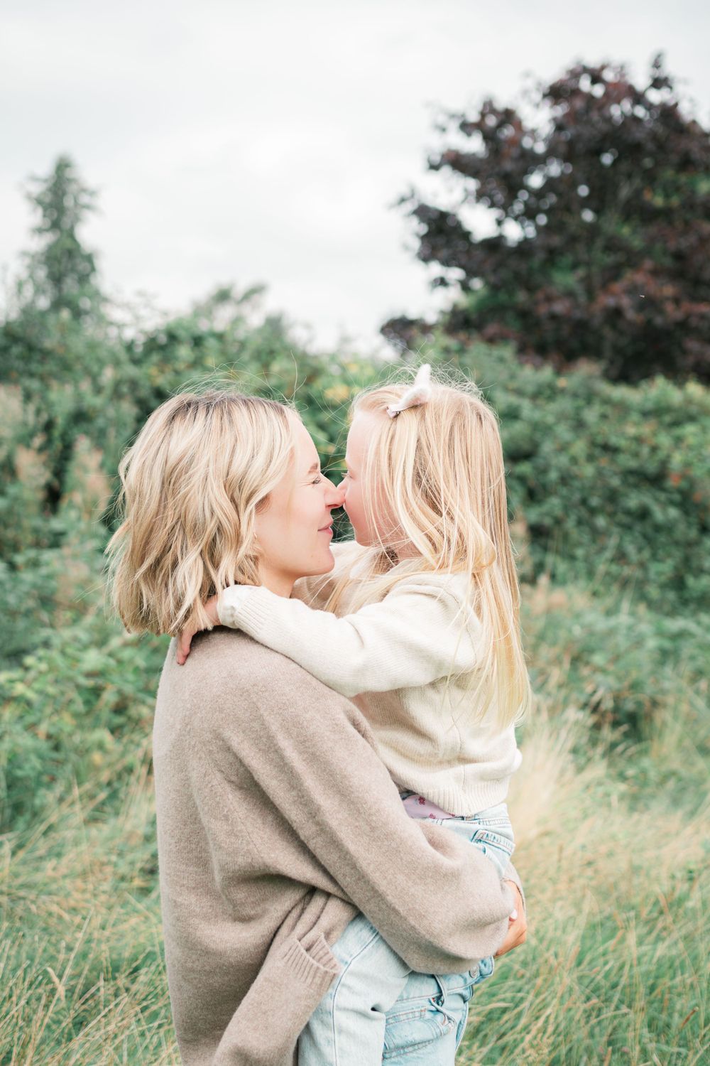 Intimate moment captured between parent and child against natural backdrop.