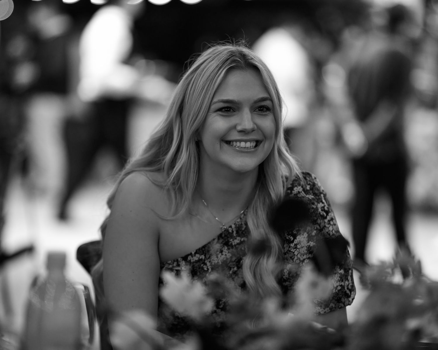 Black and white candid photo of a woman in formal attire smiling during a celebration.