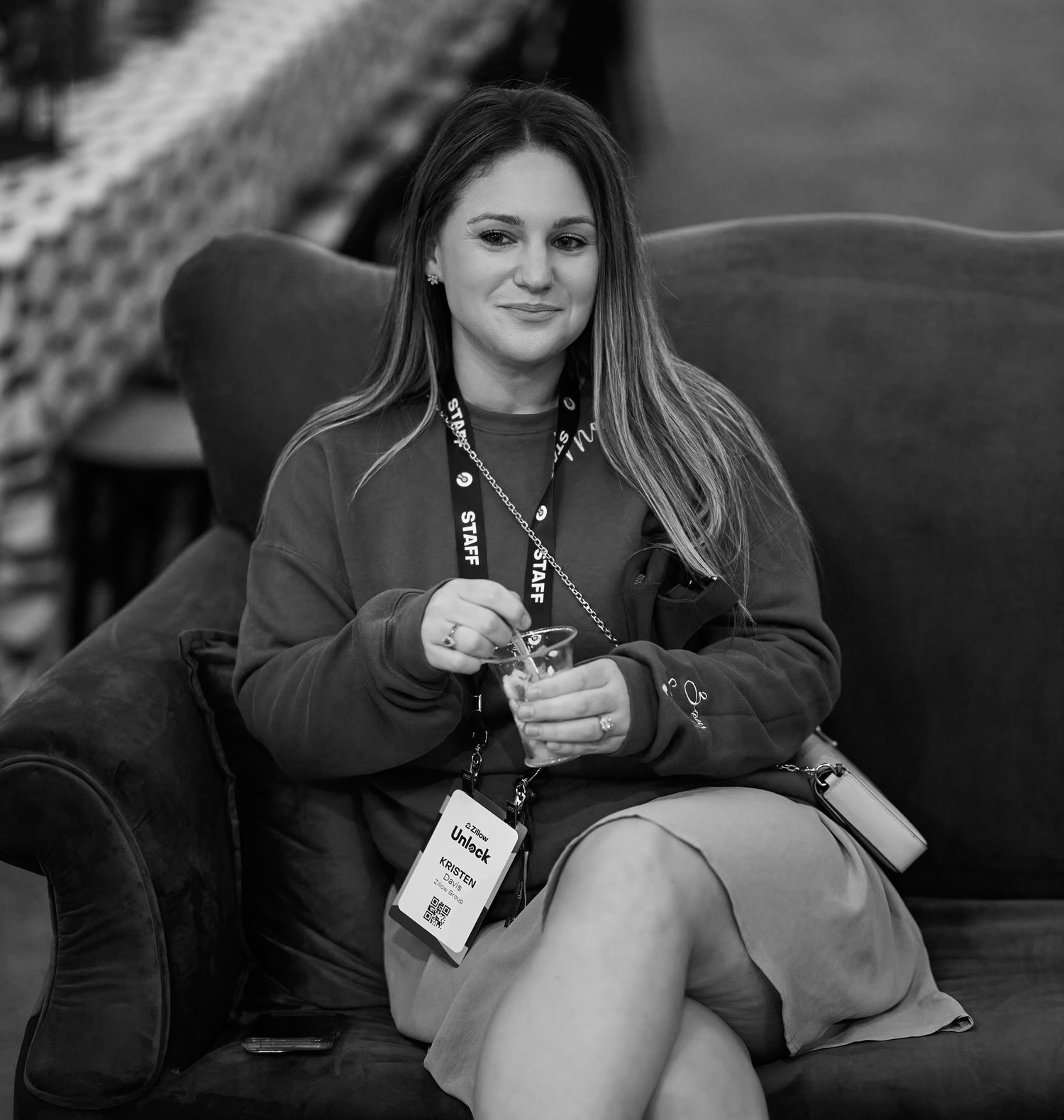 Black and white candid of patron seated on a couch wearing casual attire at Zillow event