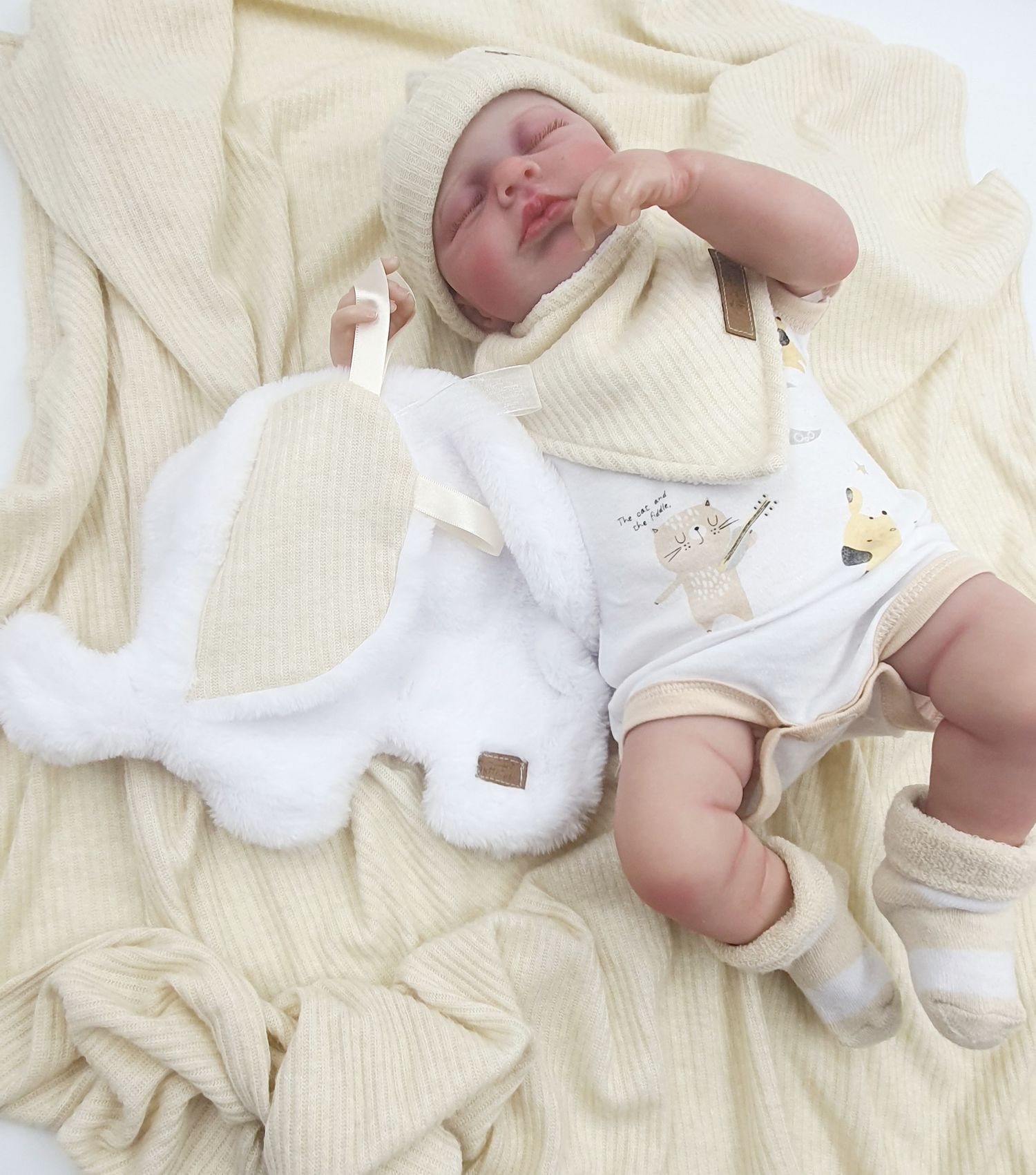 Cream colored knit blanket with white baby accessories.