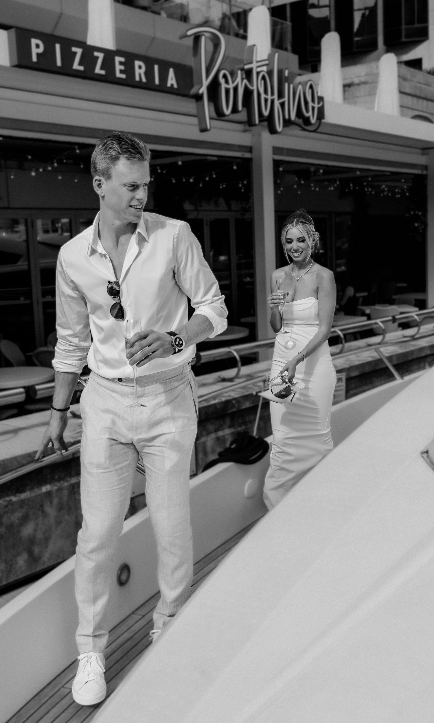 A black and white photo outside Portofino Pizzeria with a boat in view.