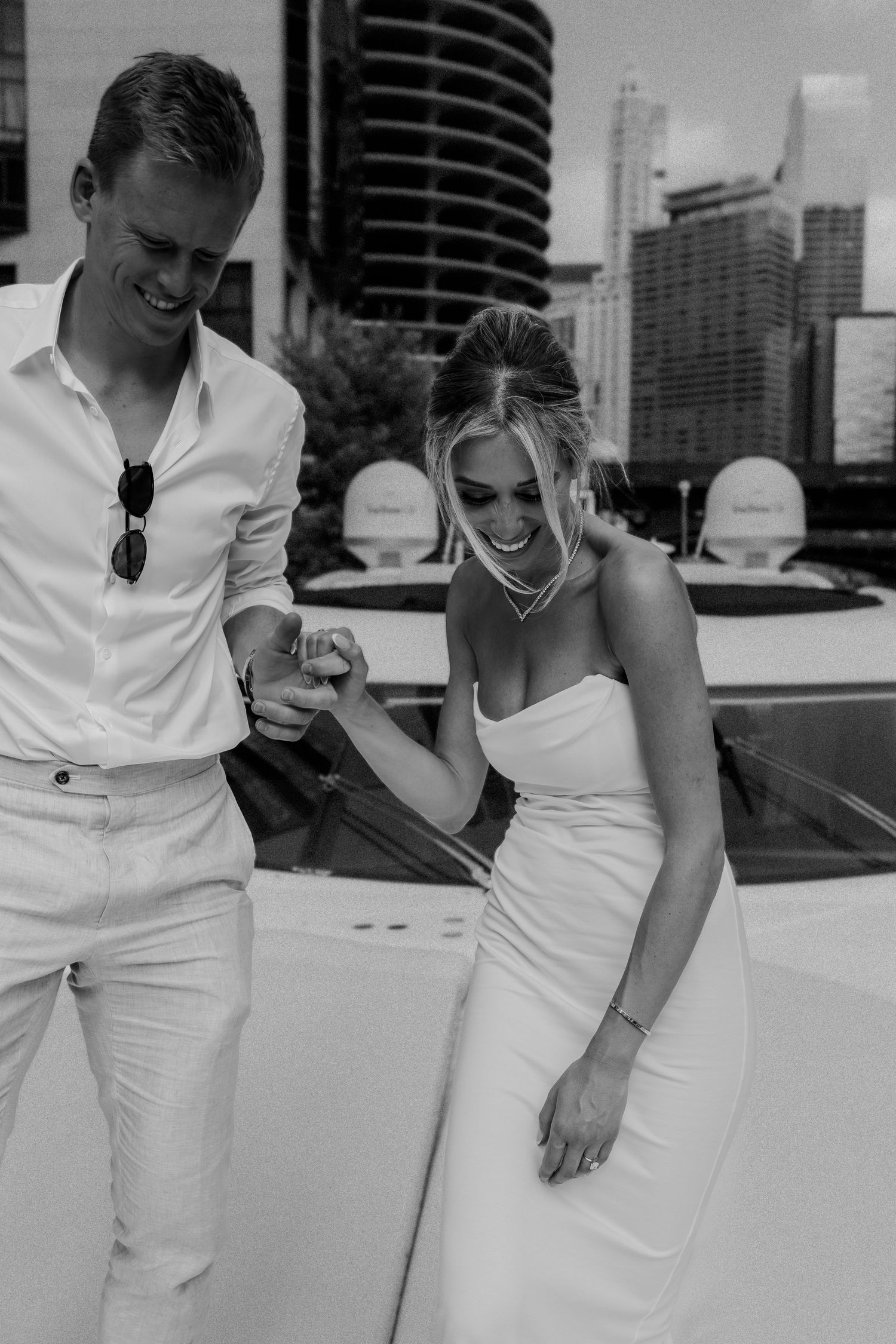 A joyful black and white moment captured on a boat with city skyline in the background.