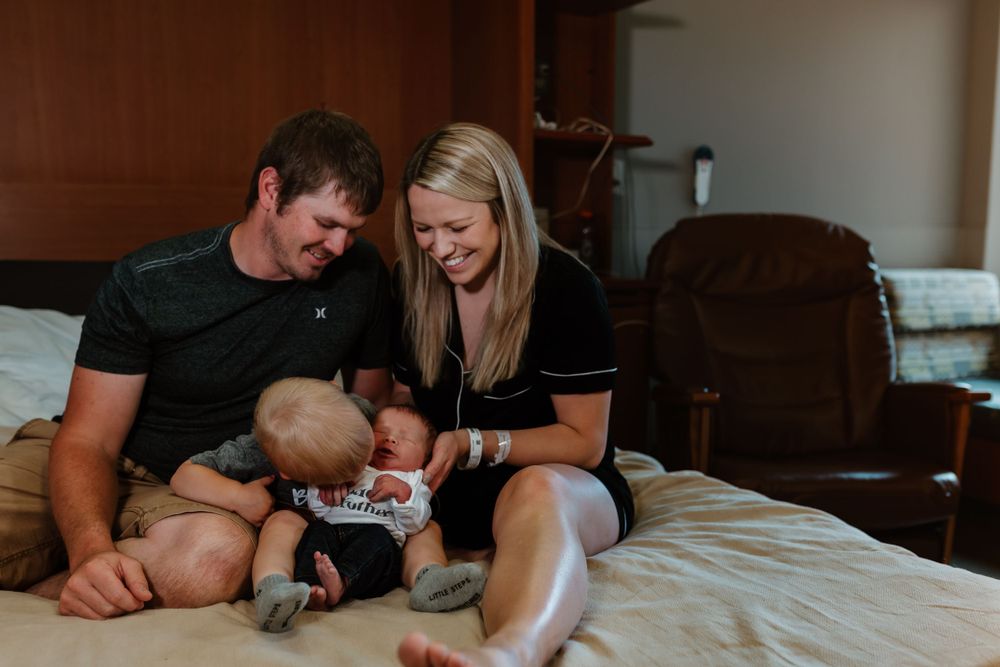 A tender family moment captured on a bed as they gaze at their baby.