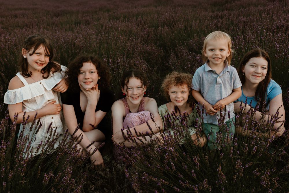 A group sits together in a field of purple heather during golden hour.