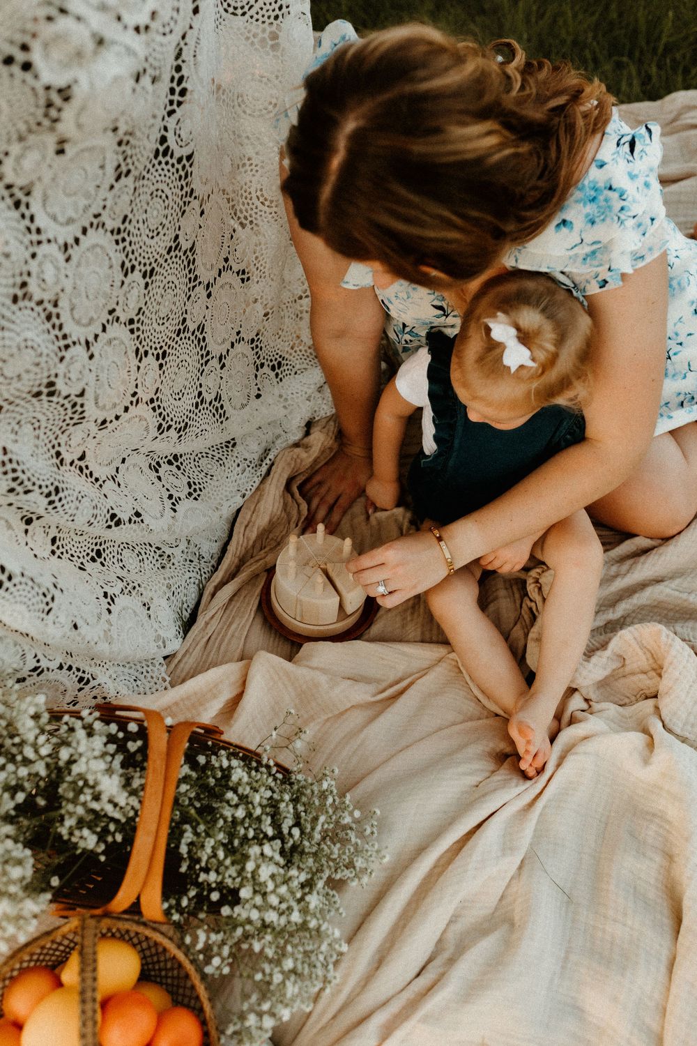 A tender moment of care captured on a picnic blanket with oranges and lace details.