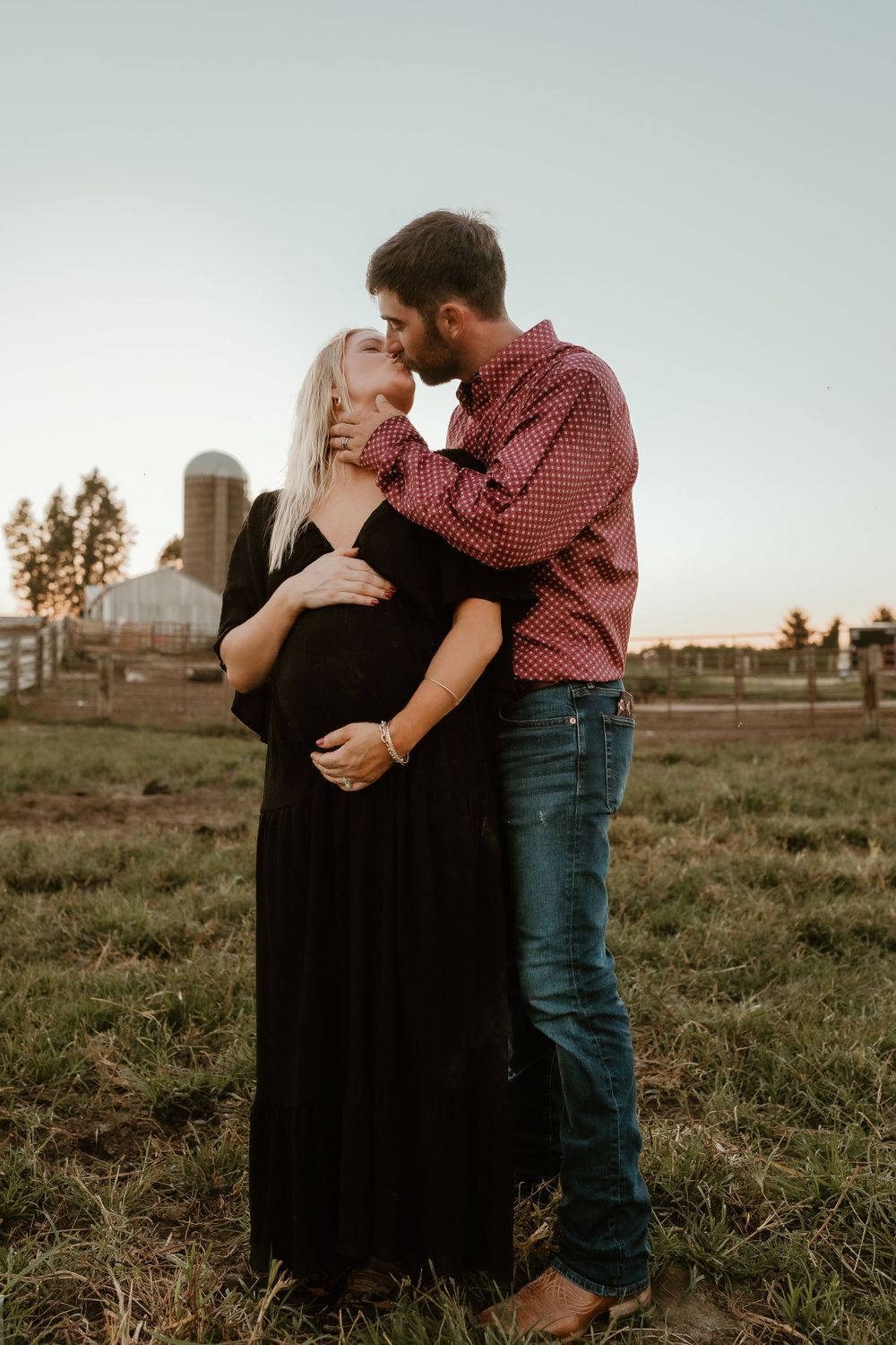 A romantic sunset moment on a farm with a silo in the background.