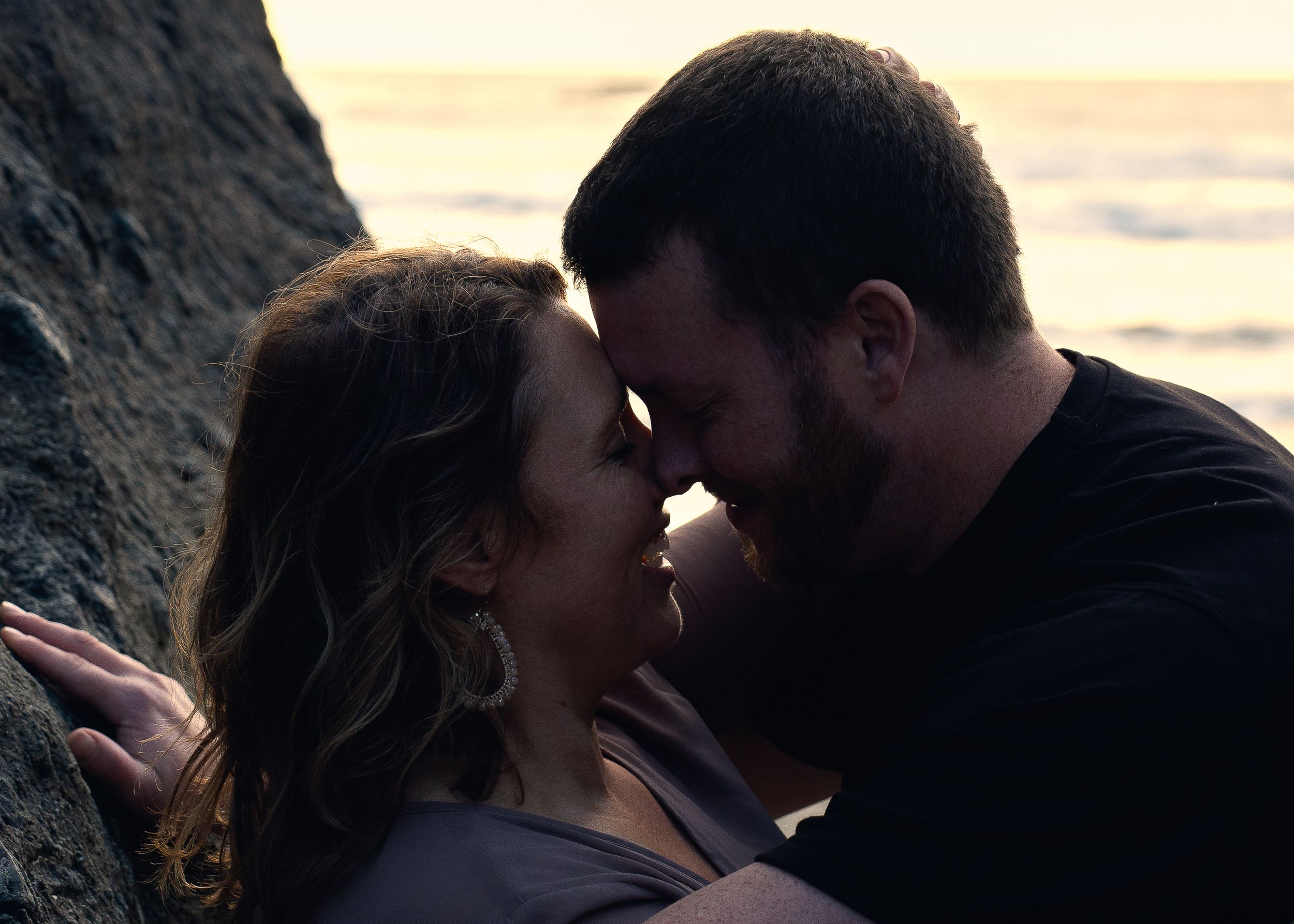 Close-up sequence showing a couple sharing intimate romantic moments during sunset by a Washington seaside cliff.