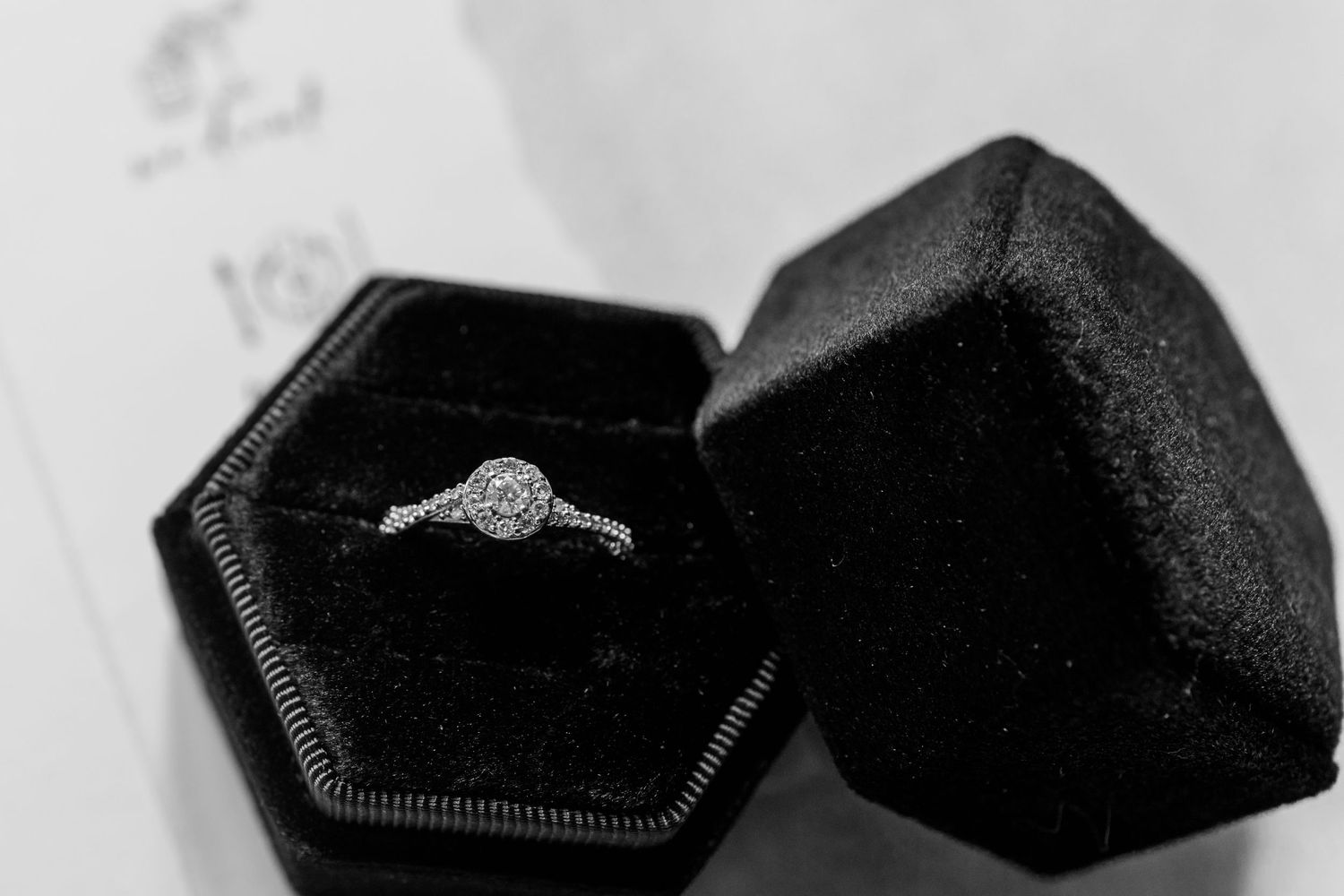 Diamond engagement ring nestled in a black velvet ring box with dramatic lighting.