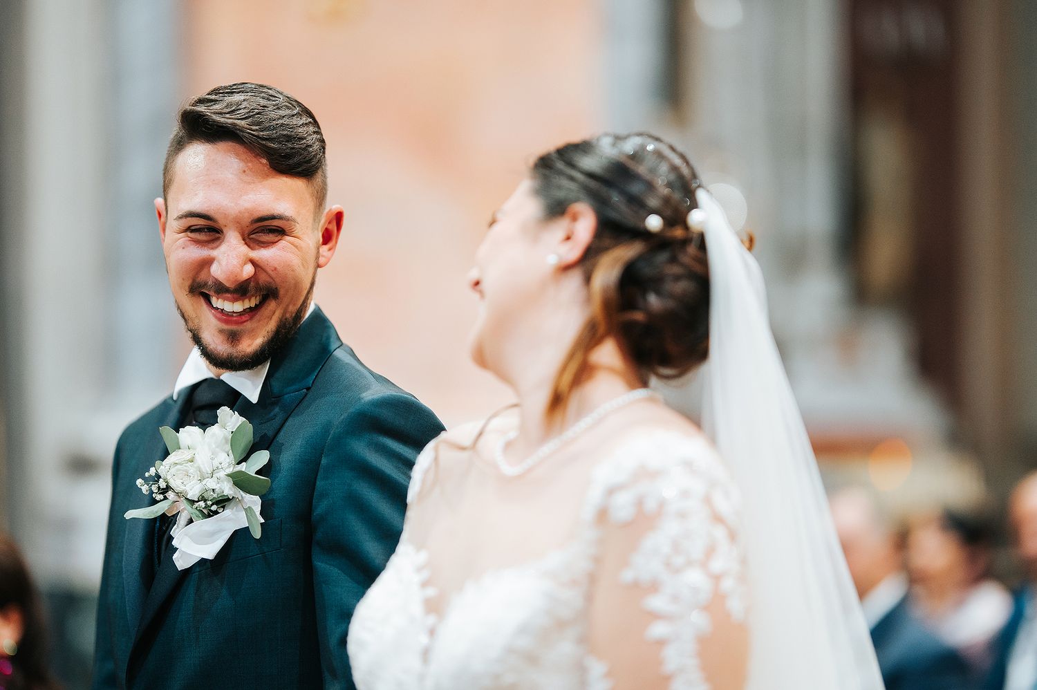 Laughing bride and groom sharing a joyful moment together outside an ornate church after ceremony.