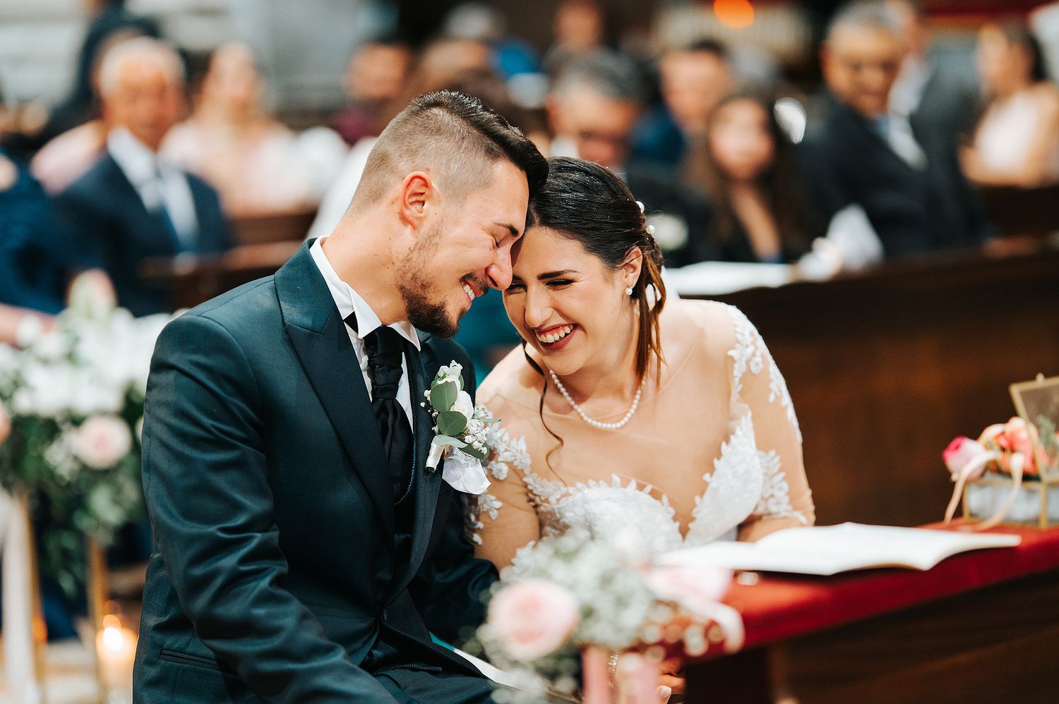 Happy bride and groom laughing together at altar during wedding ceremony in ornate church.