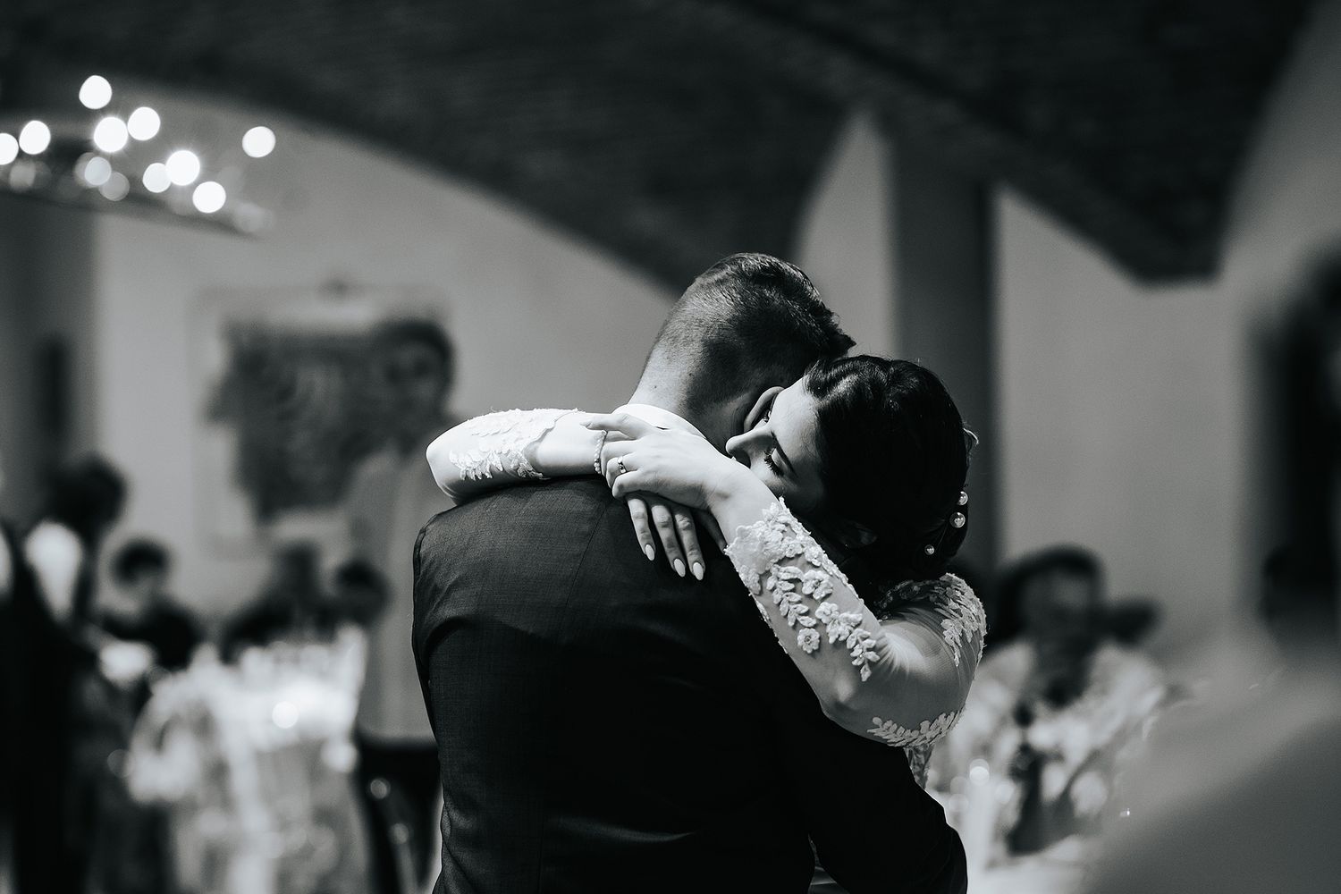 Bride and groom share an intimate first dance embrace in black and white wedding photo.
