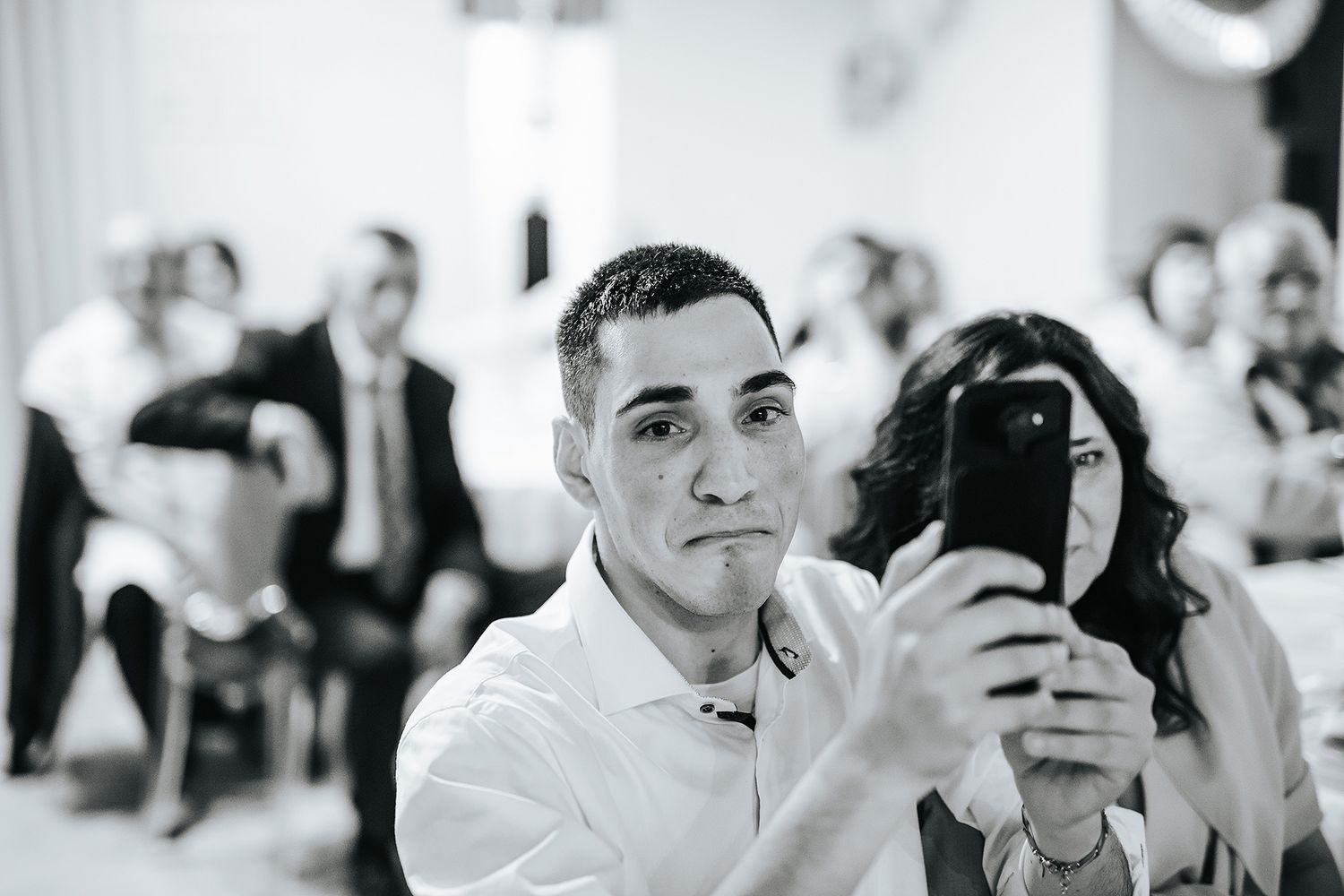 Wedding guest takes selfie with smartphone during wedding reception ceremony.