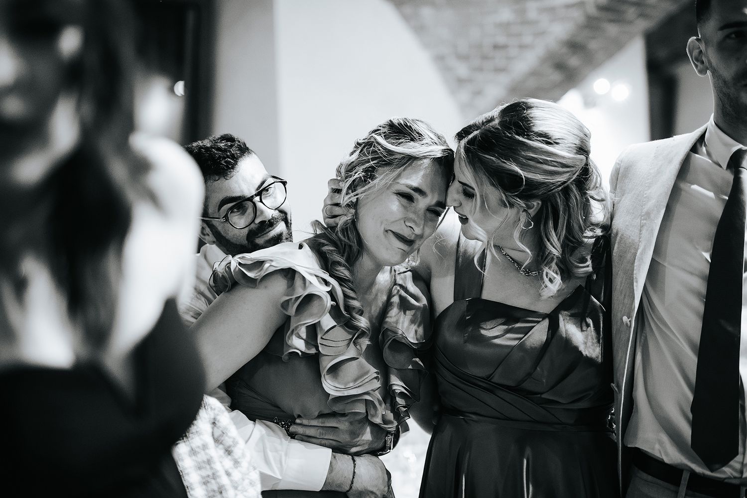 Wedding guests laughing and embracing during fun outdoor wedding celebration in black and white.