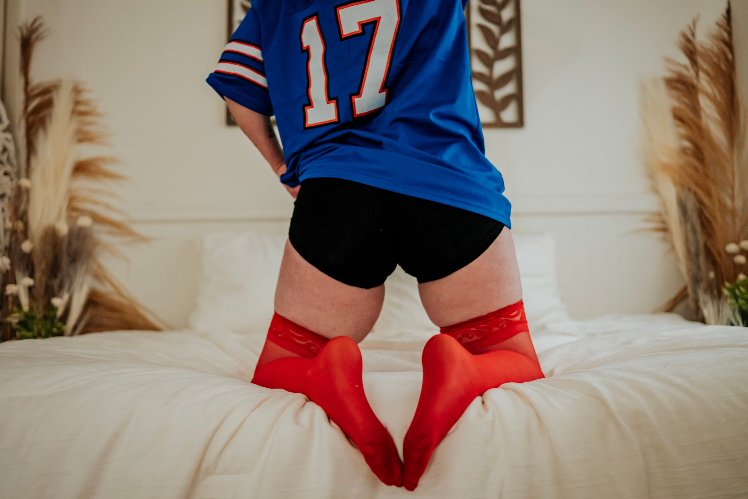Person wearing jersey number 17 relaxing on white bedding with decorative wall art.