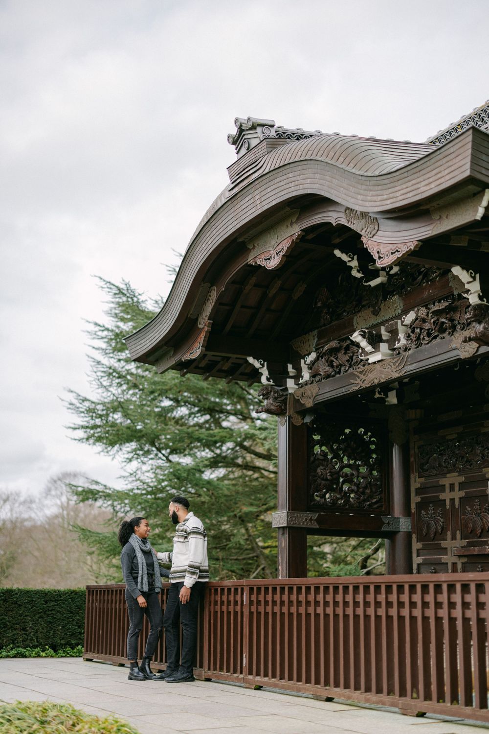 A couple admiring the architecture of a traditional Japanese pavilion with curved roof and wooden details.