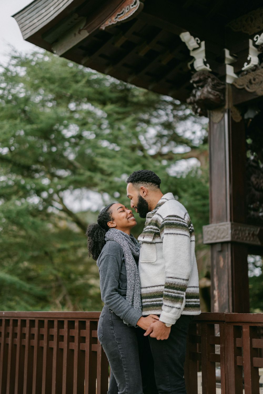 A romantic moment shared between a couple under the eaves of a traditional Japanese pavilion.