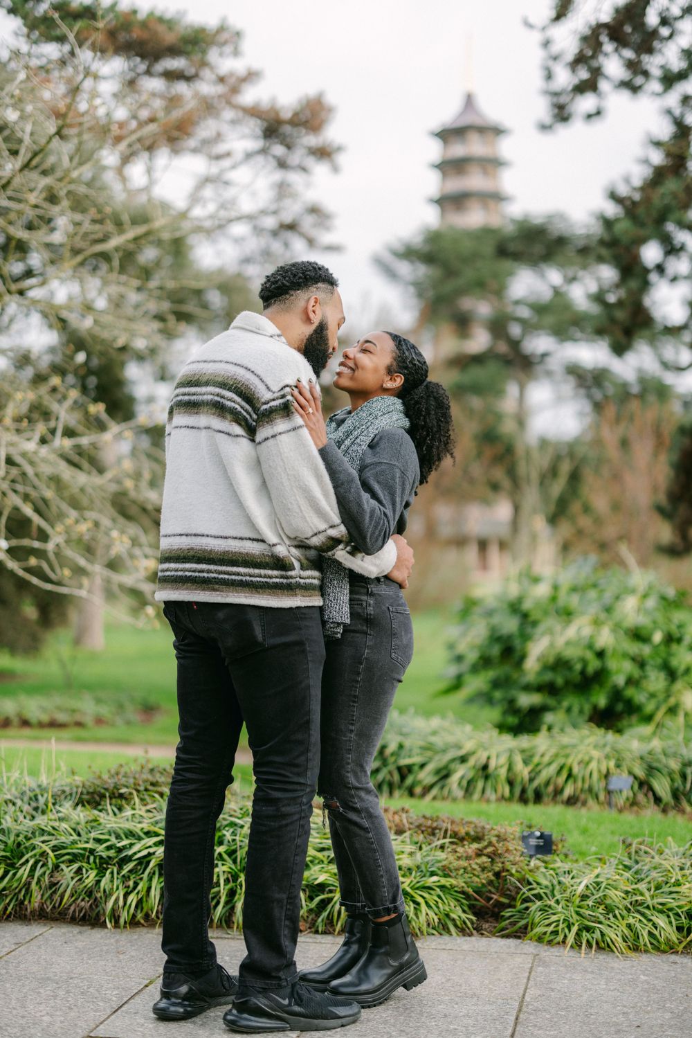 A couple embracing in front of a pagoda tower in a Japanese garden setting.