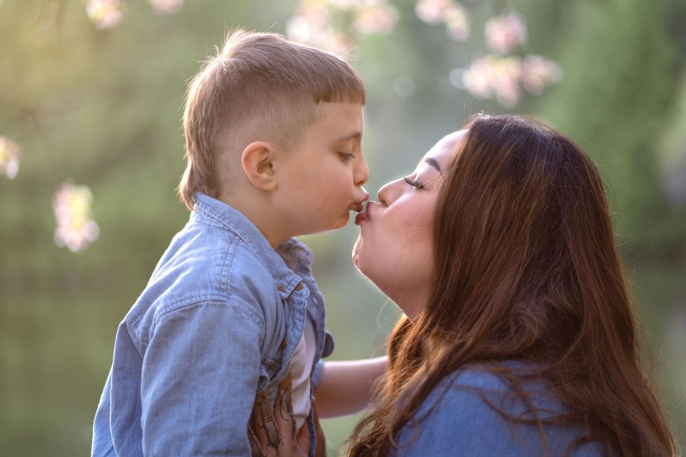 Mother and child share joyful moment under blooming spring trees.
