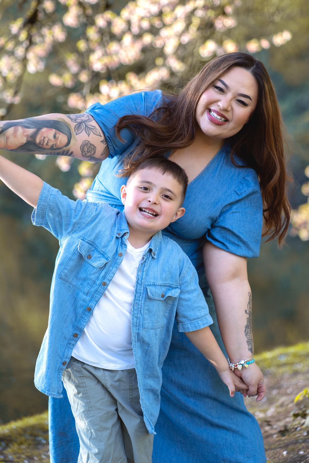 Mother and child in matching denim outfits laugh together outdoors in spring setting.